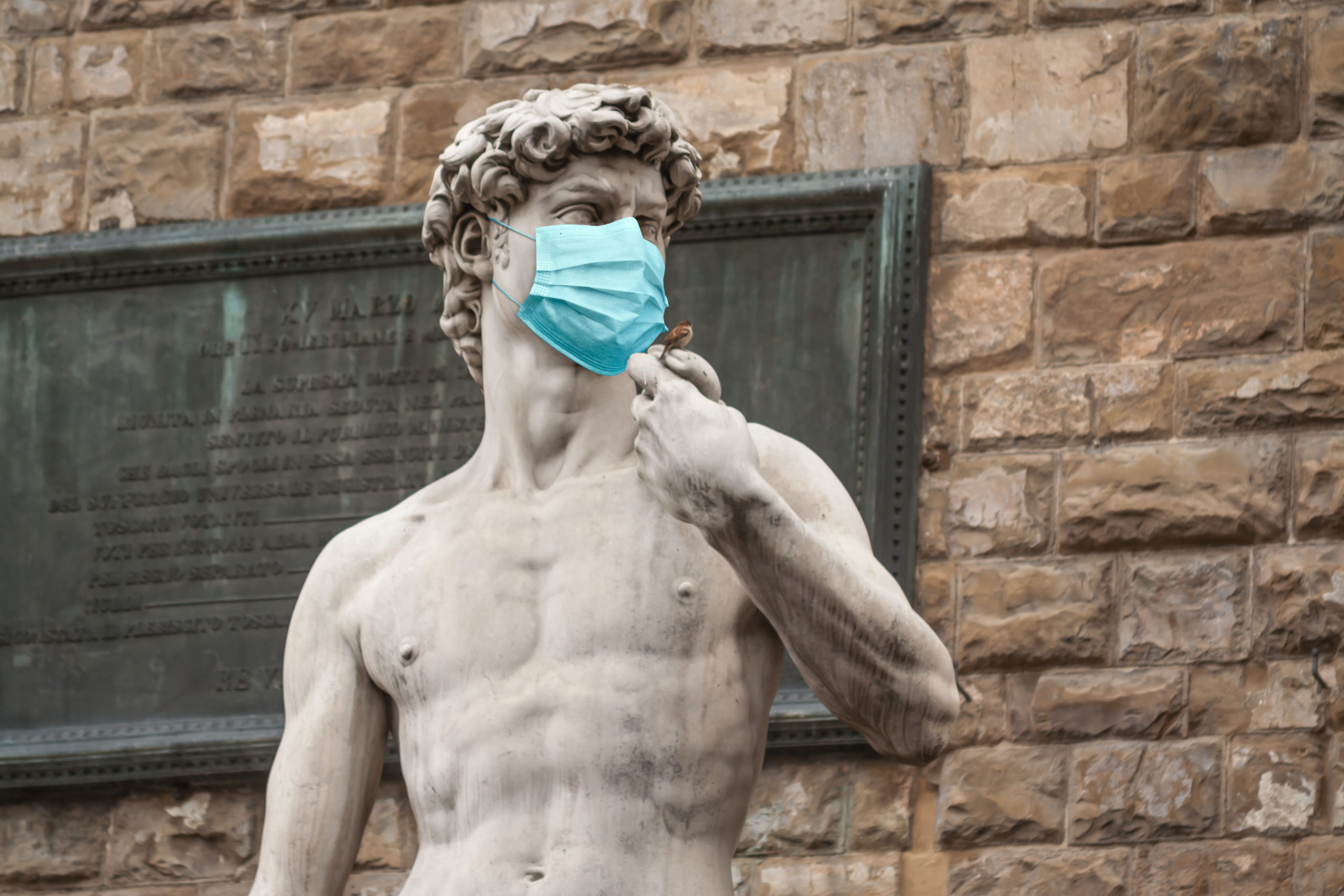 The Statue Of David in the Piazza della Signoria In Italy Wearing Blue Protective Medical Face Mask