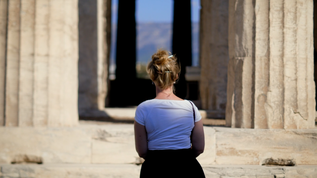 A woman is looking at ancient Greek columns