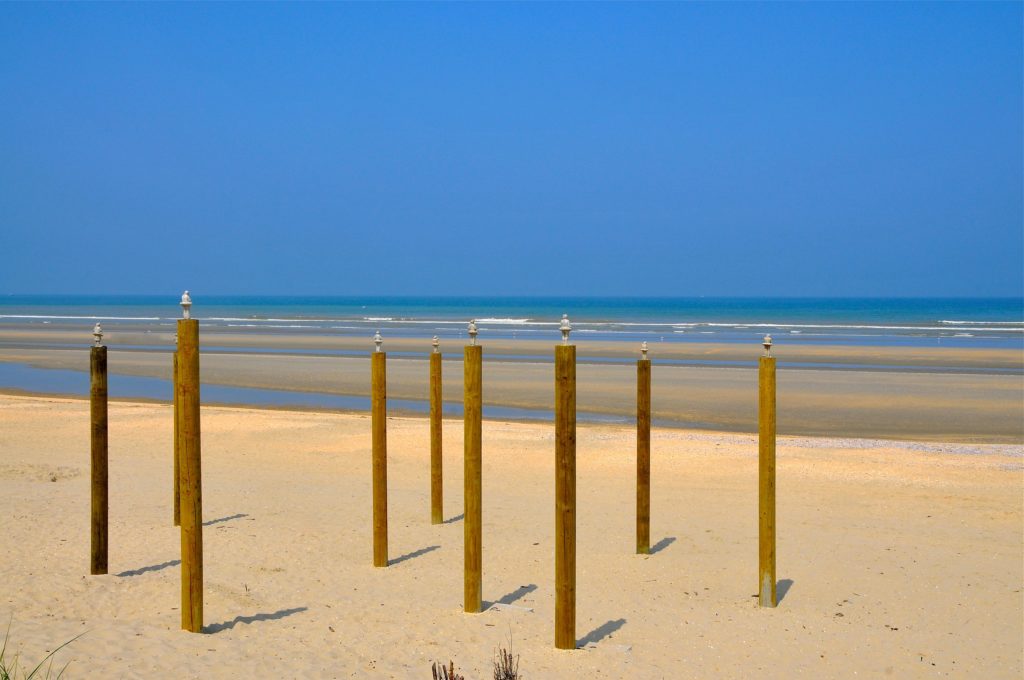 Little statues on a beach waiting for the sea level to rise.